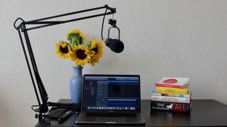 Desktop setup for recording a podcast with a microphone connected to a laptop