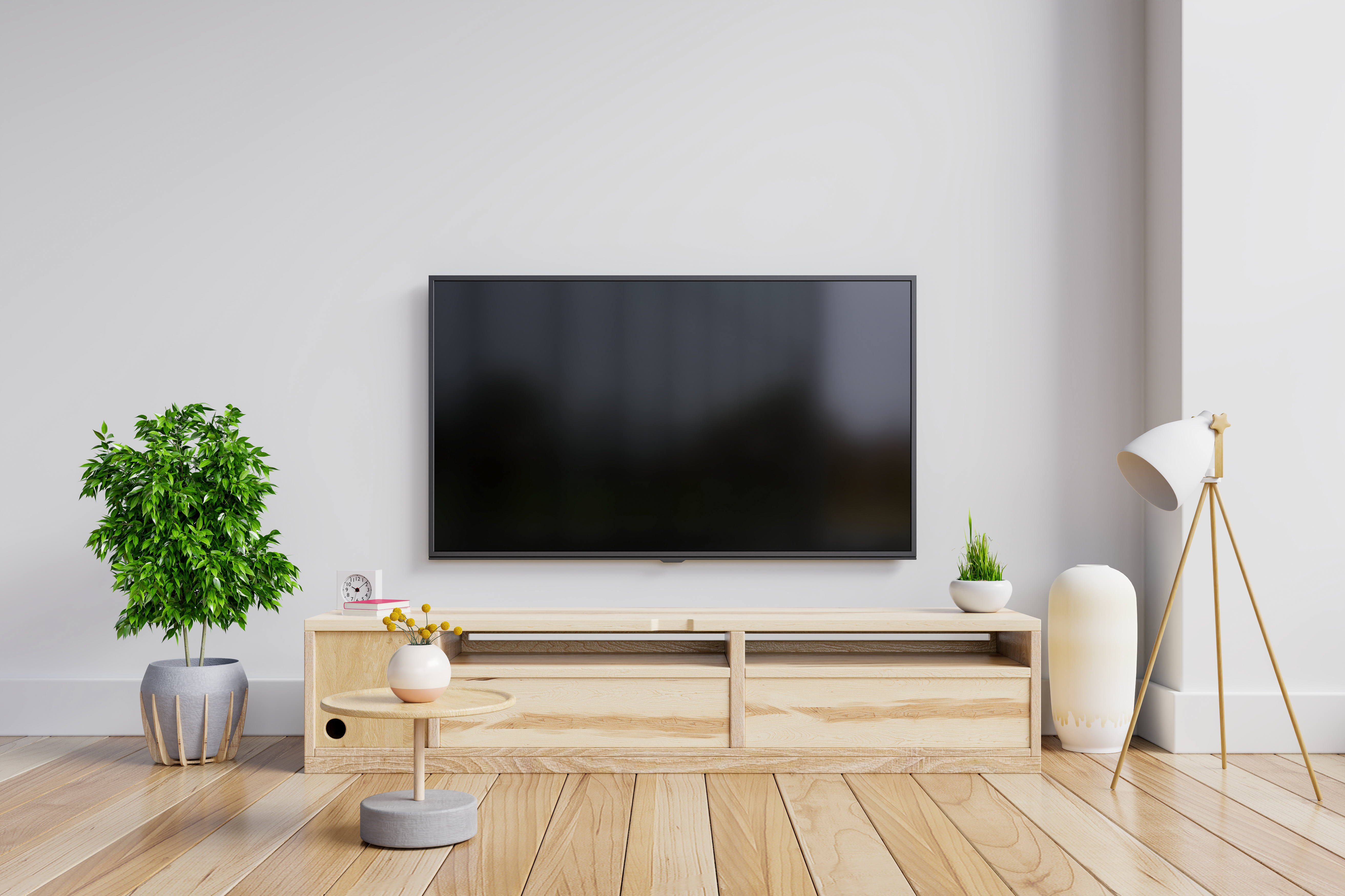 HDTV with no content displayed mounted on a wall in a living room setting with a small table in the foreground