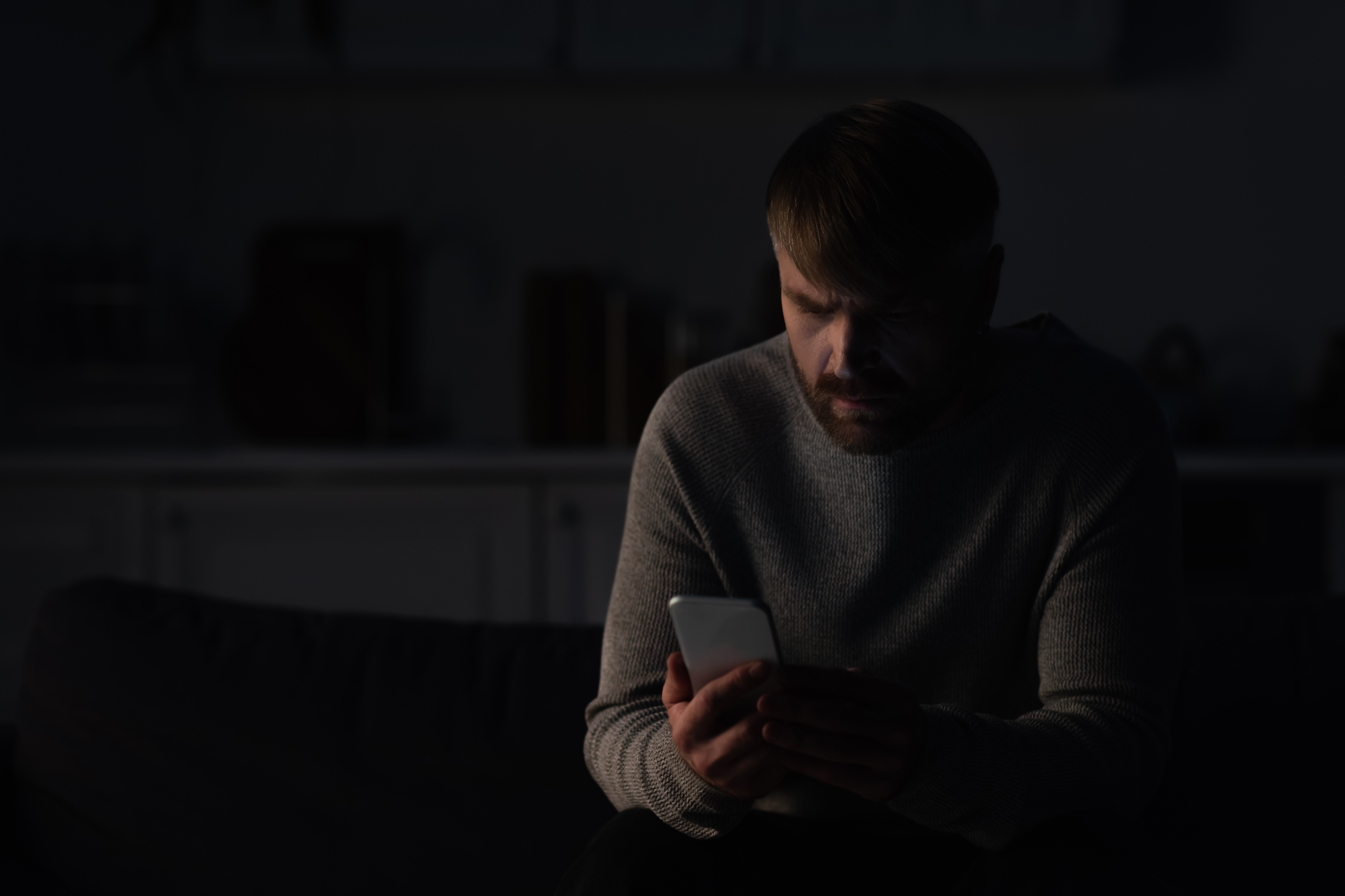man looking at phone in the dark