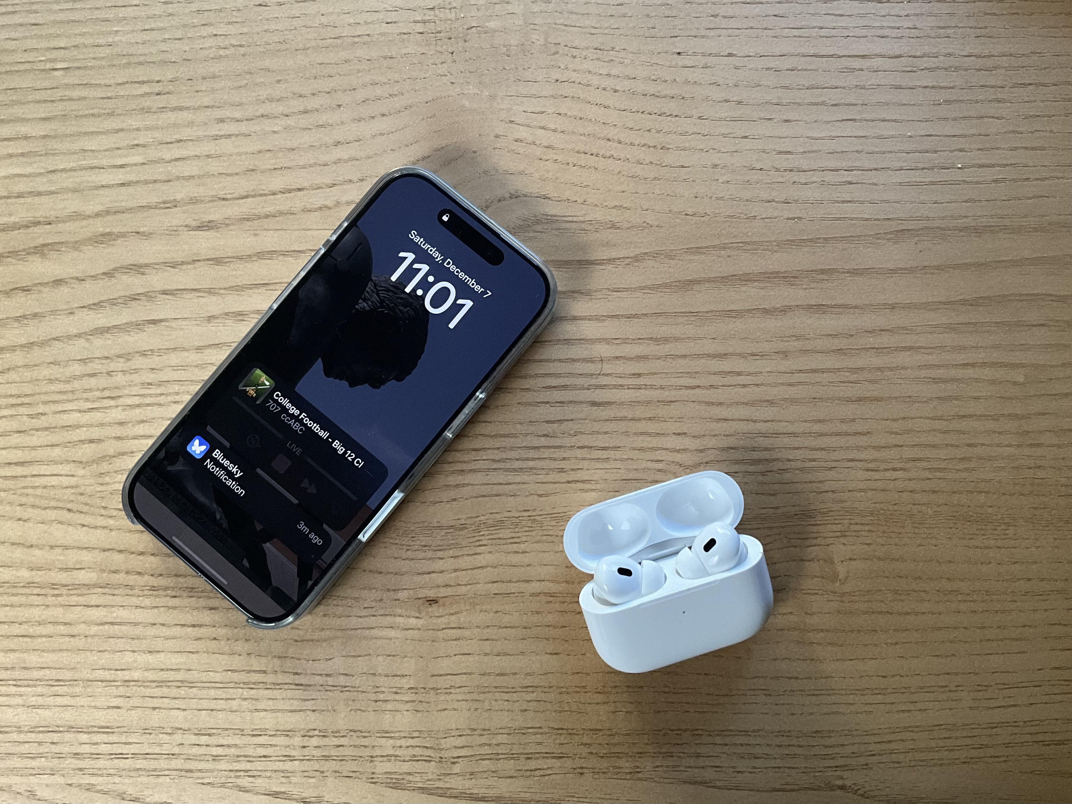 iPhone 16 Pro and Airpods on a wood background